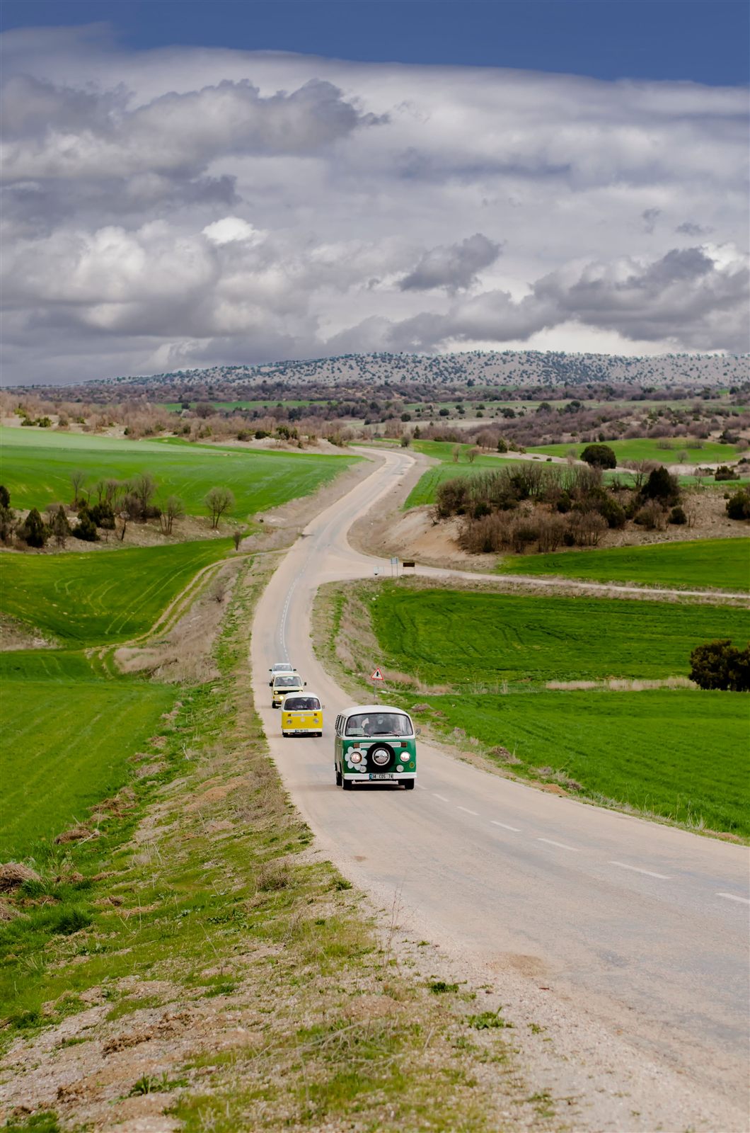 Furgonetas clásicas circulando en caravana por una carretera rural