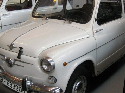 SEAT 600 blanco expuesto en un museo, visto en tres cuartos delantero, con otro 600 detrás.